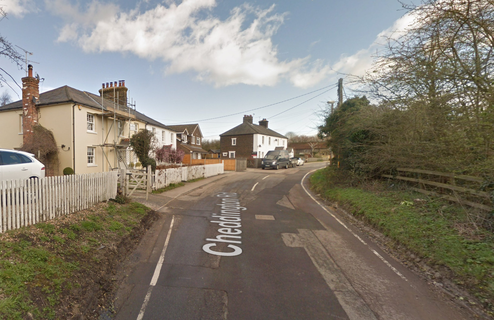 Image of Cheddington Road with railway bridge behind, showing close proximity of houses, vehicles parked on bend, and lack of visibiliity.